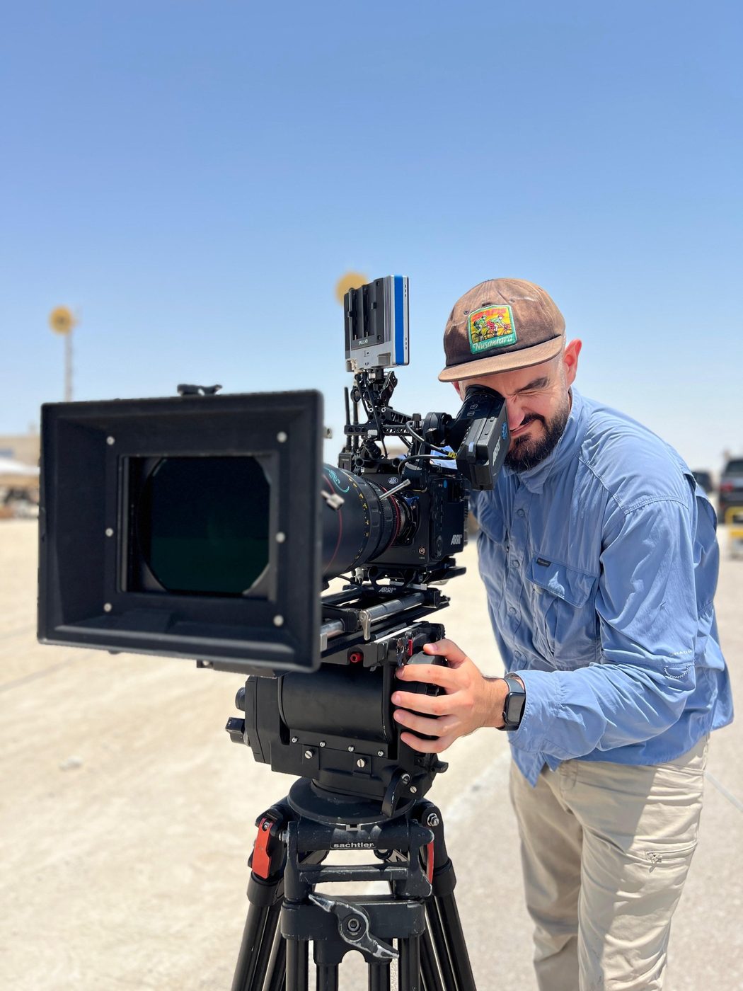 Rian McLoughlin looking through the eyepiece of an ARRI camera on a Sachtler tripod