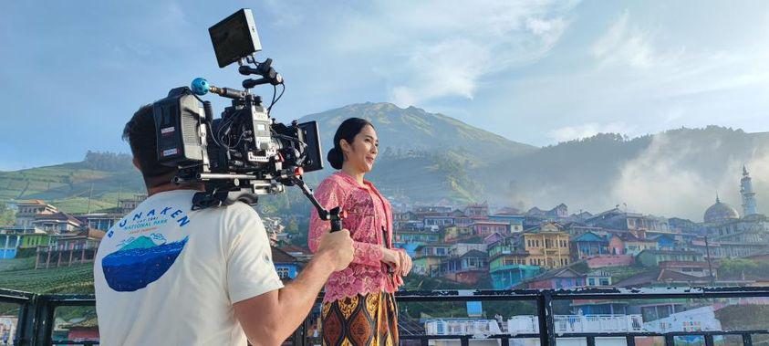 Rian shoulder-operating an ALEXA as talent stands on a terrace above a hillside town in Indonesia
